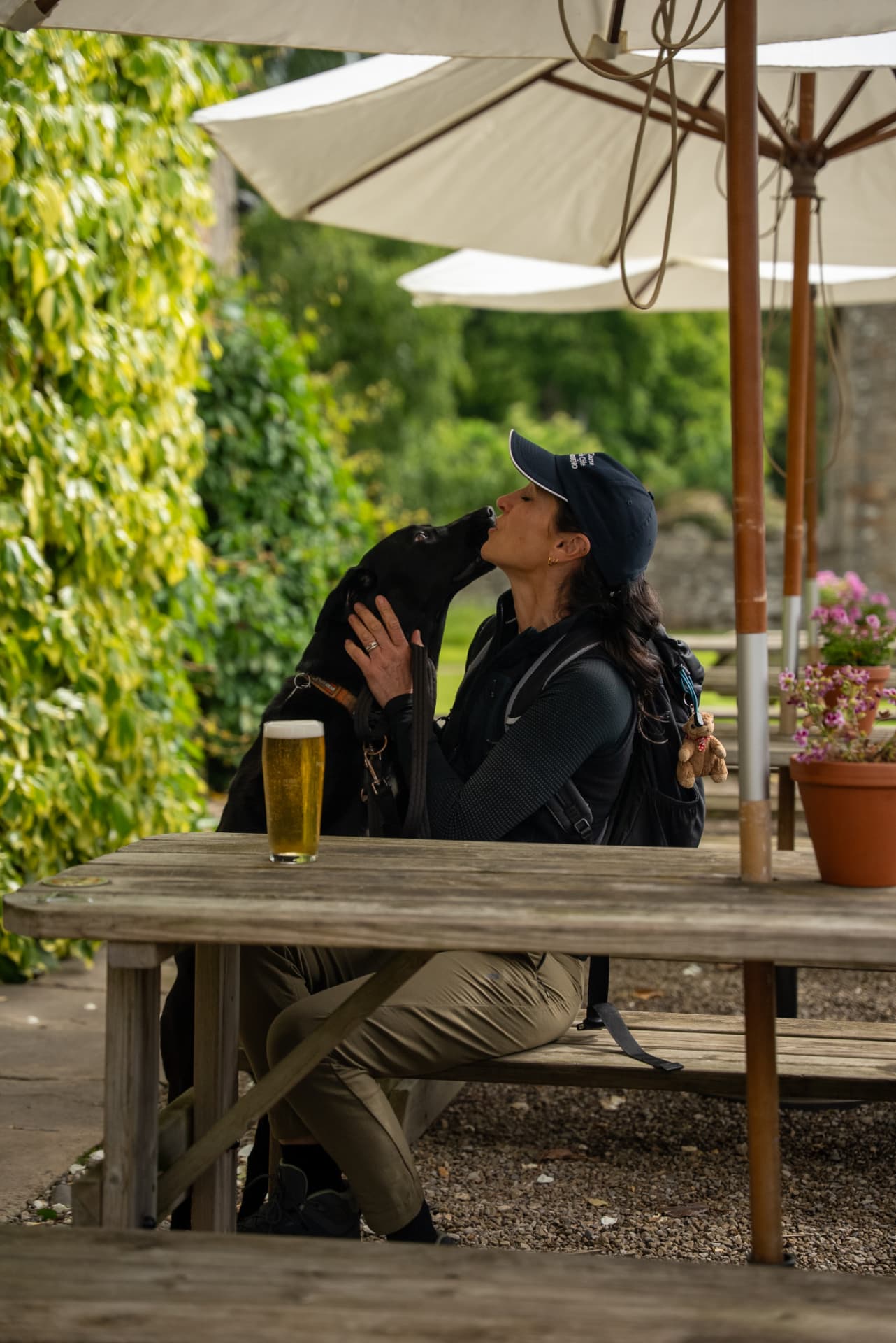 A walker greeting her dog at a pub garden table under parasols