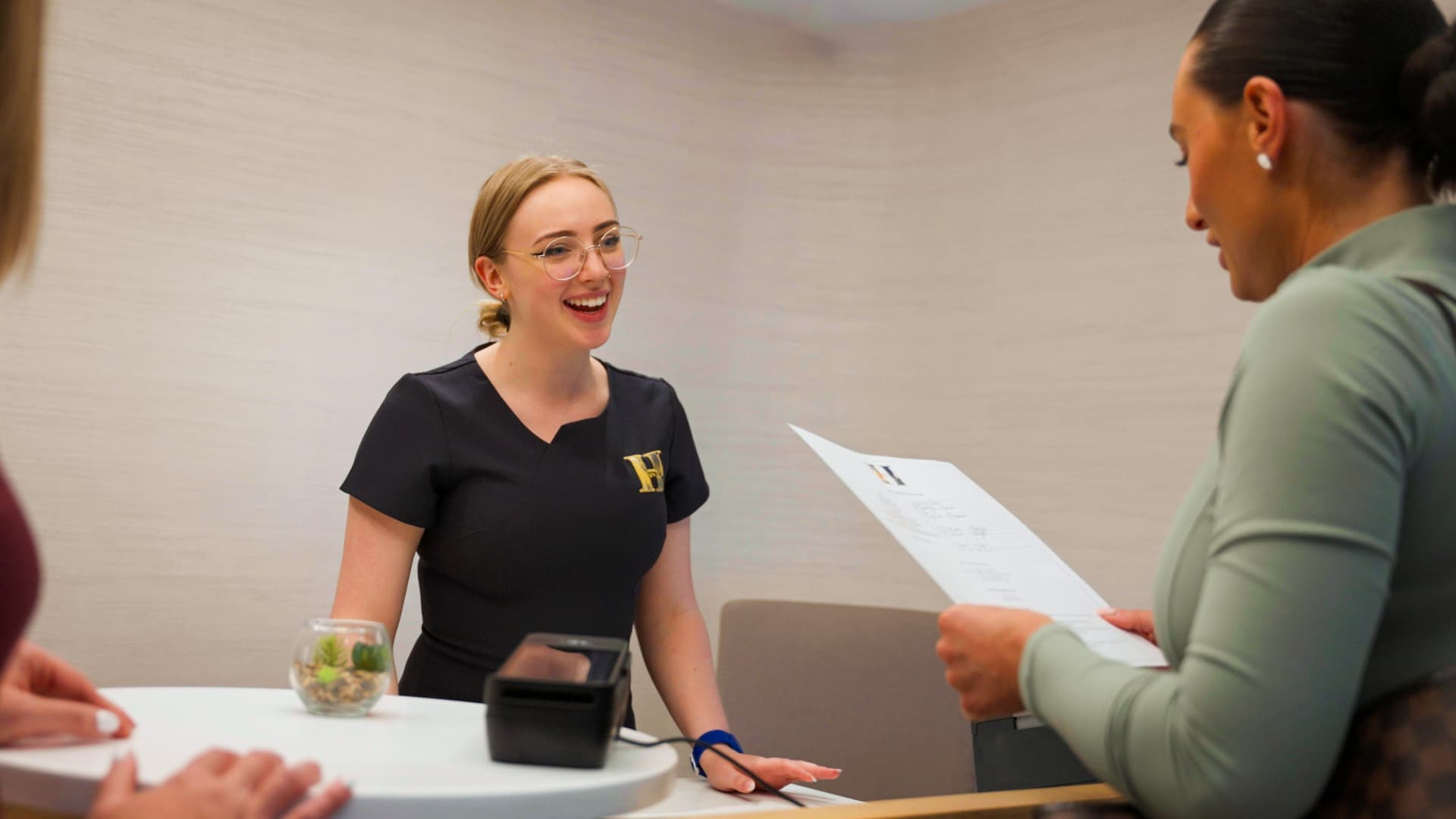 A smiling receptionist welcoming guests at a spa desk