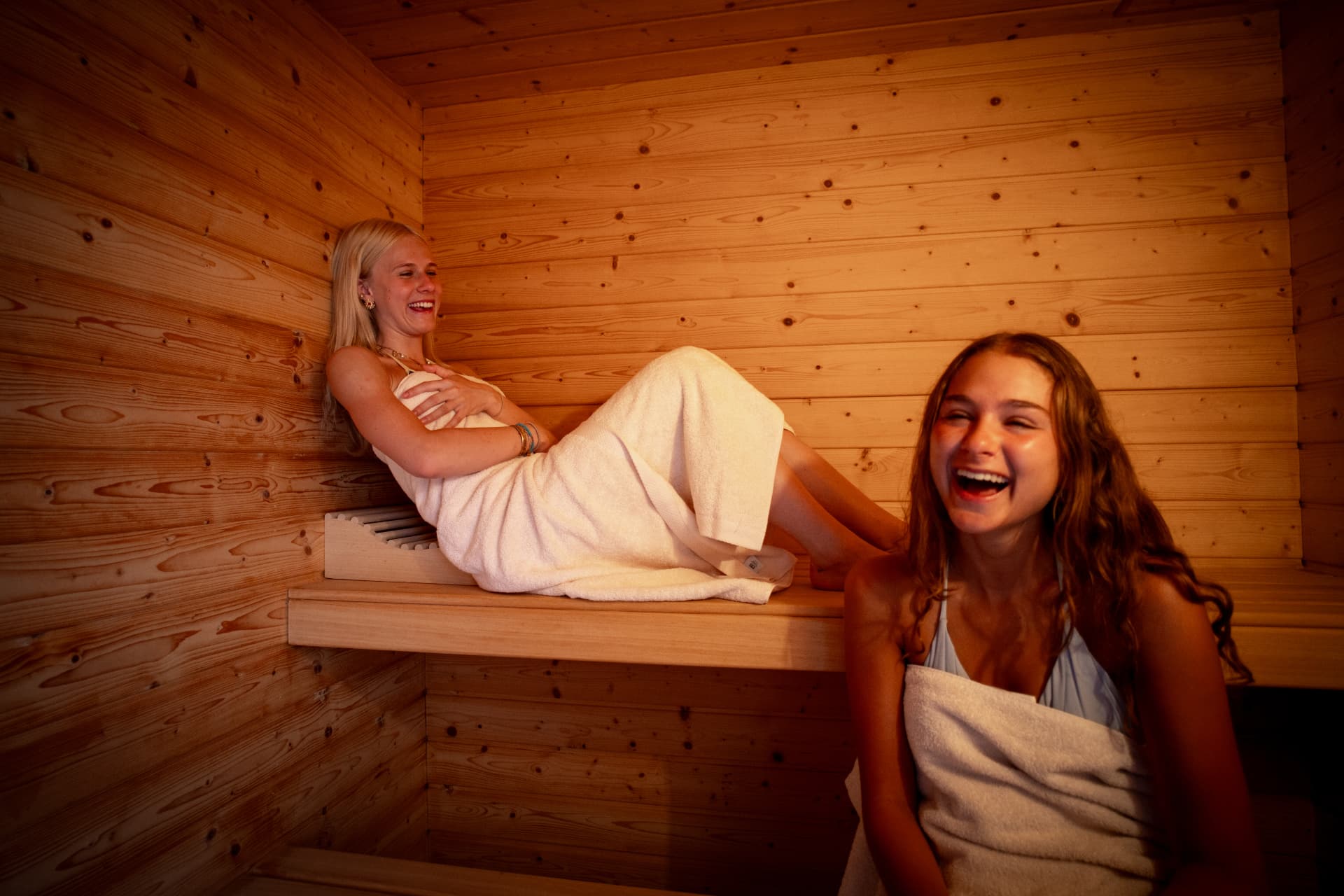 Two guests laughing together in a wood-lined hotel sauna