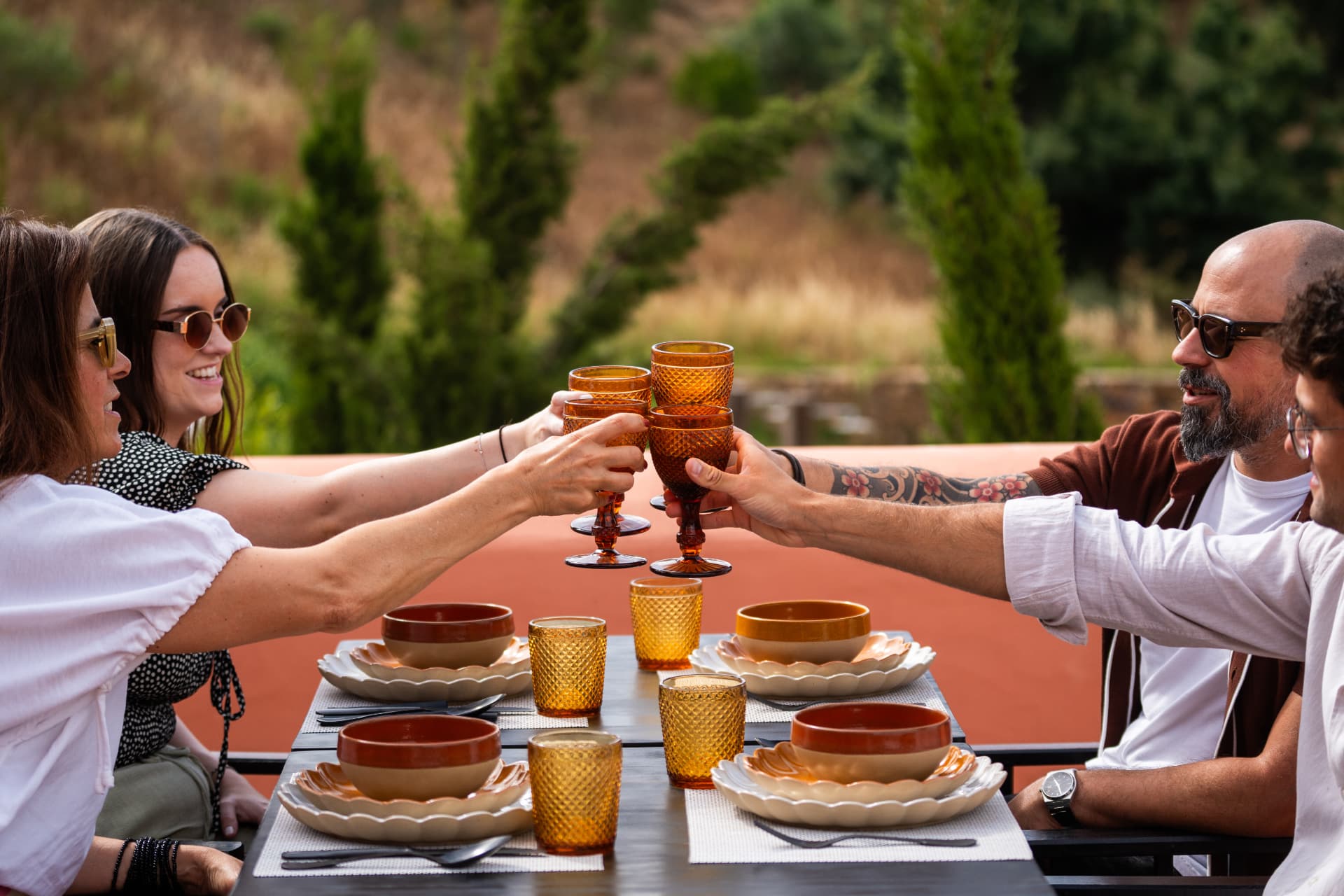 Friends raising amber glasses at a terracotta terrace table