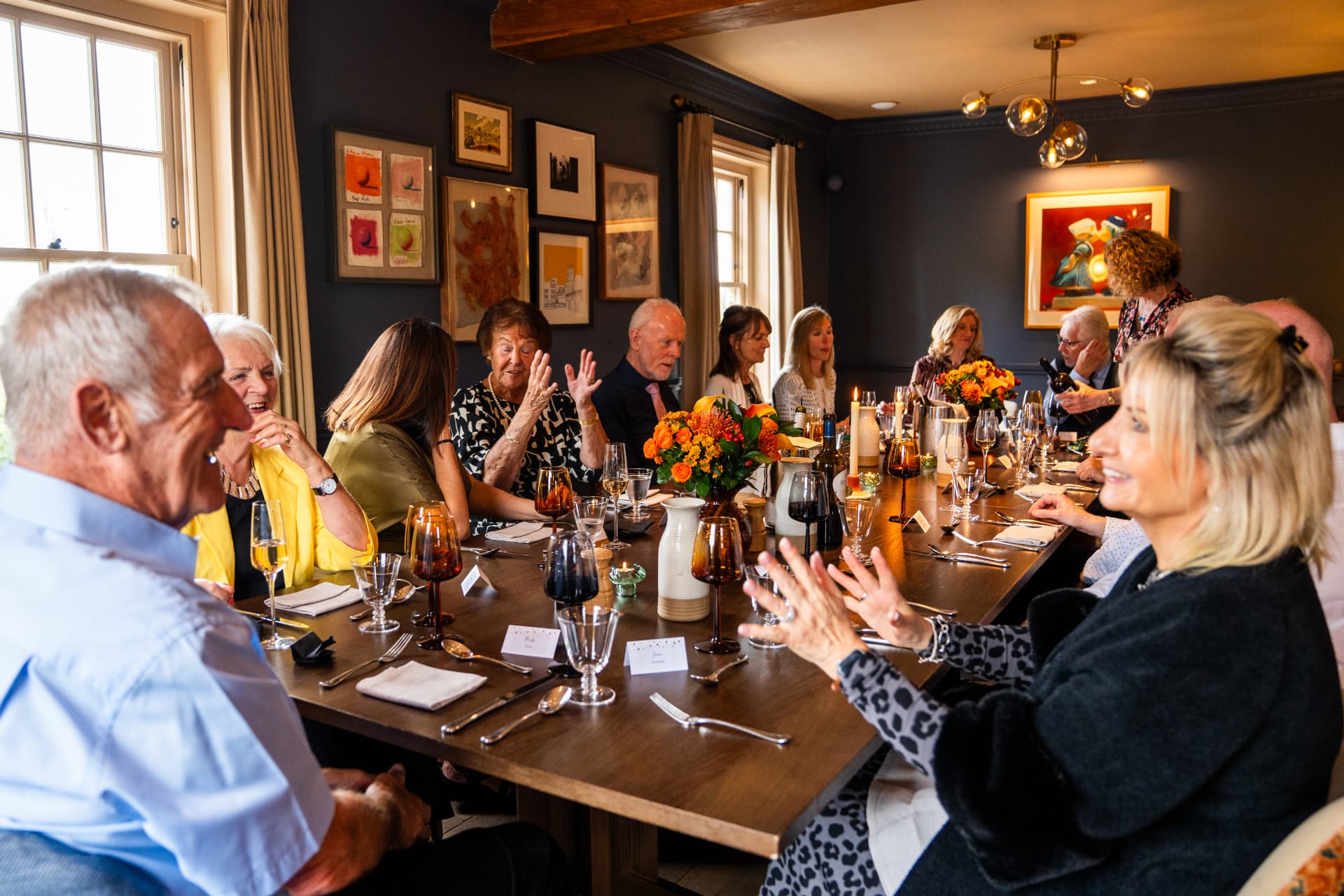 A lively private dining party around a long candlelit table