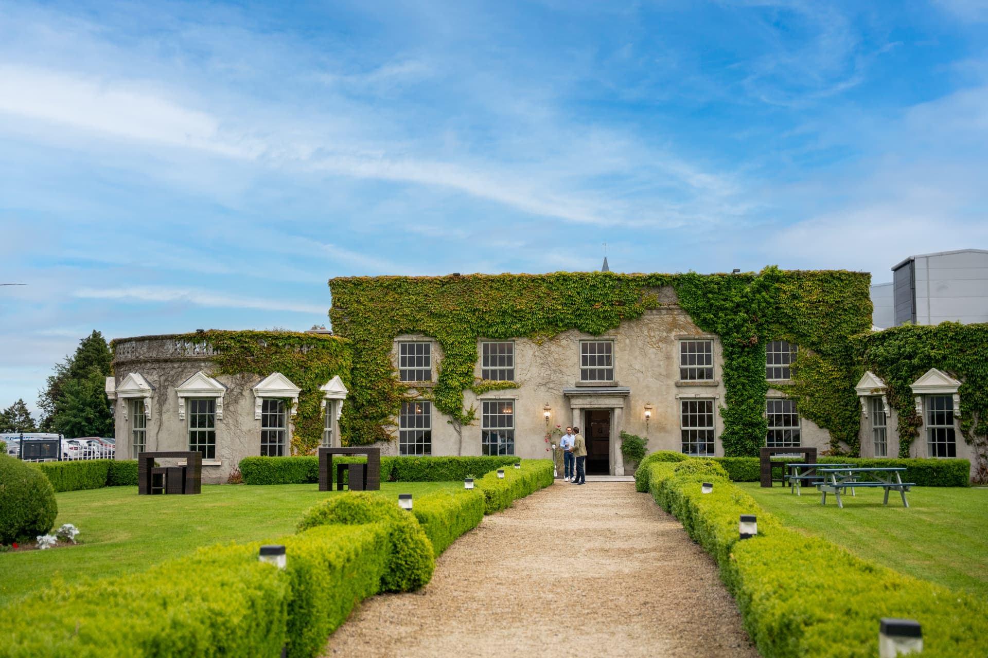An ivy-clad Georgian country house hotel with a gravel path through clipped hedges